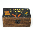 Wooden box with 'Trust the Universe' text and celestial designs on a black background