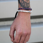Hand wearing two bracelets with a blurred background