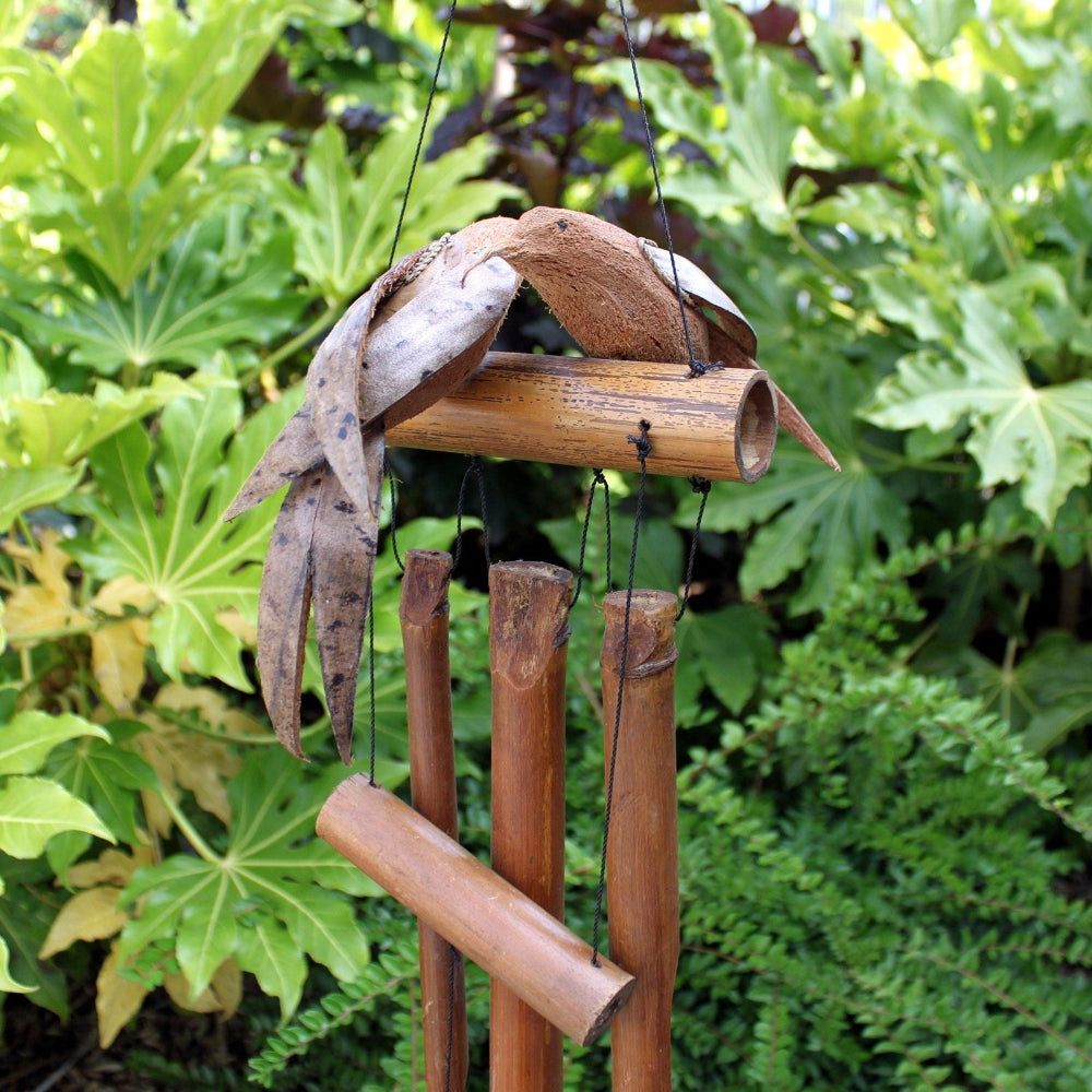 Bamboo wind chime with natural elements against a green leafy background