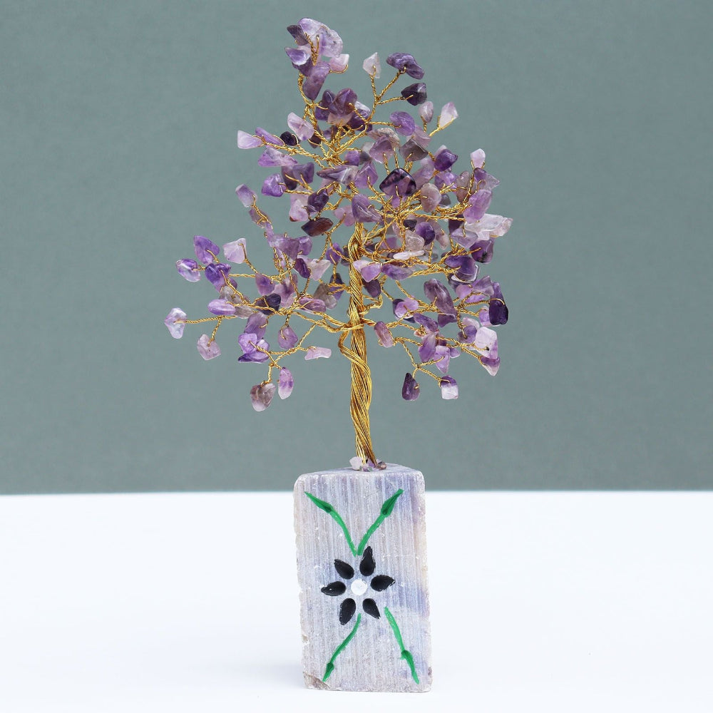 Decorative crystal tree on a stone base with a floral design against a gray background