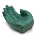 Decorative green hand-shaped object with engraved text on a white background
