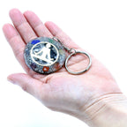 Keychain with a decorative design held in a hand against a white background