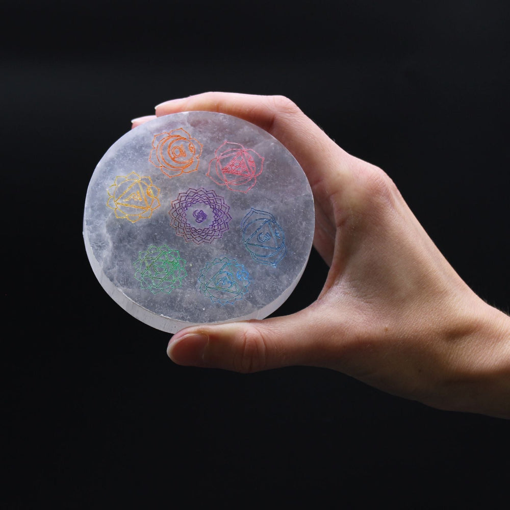 Hand holding a round, translucent disc with colorful patterns on a black background