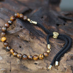 Necklace with brown beaded chain and black cord on a wooden surface