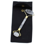 Glowing crystal face roller with gold accents on a black pouch