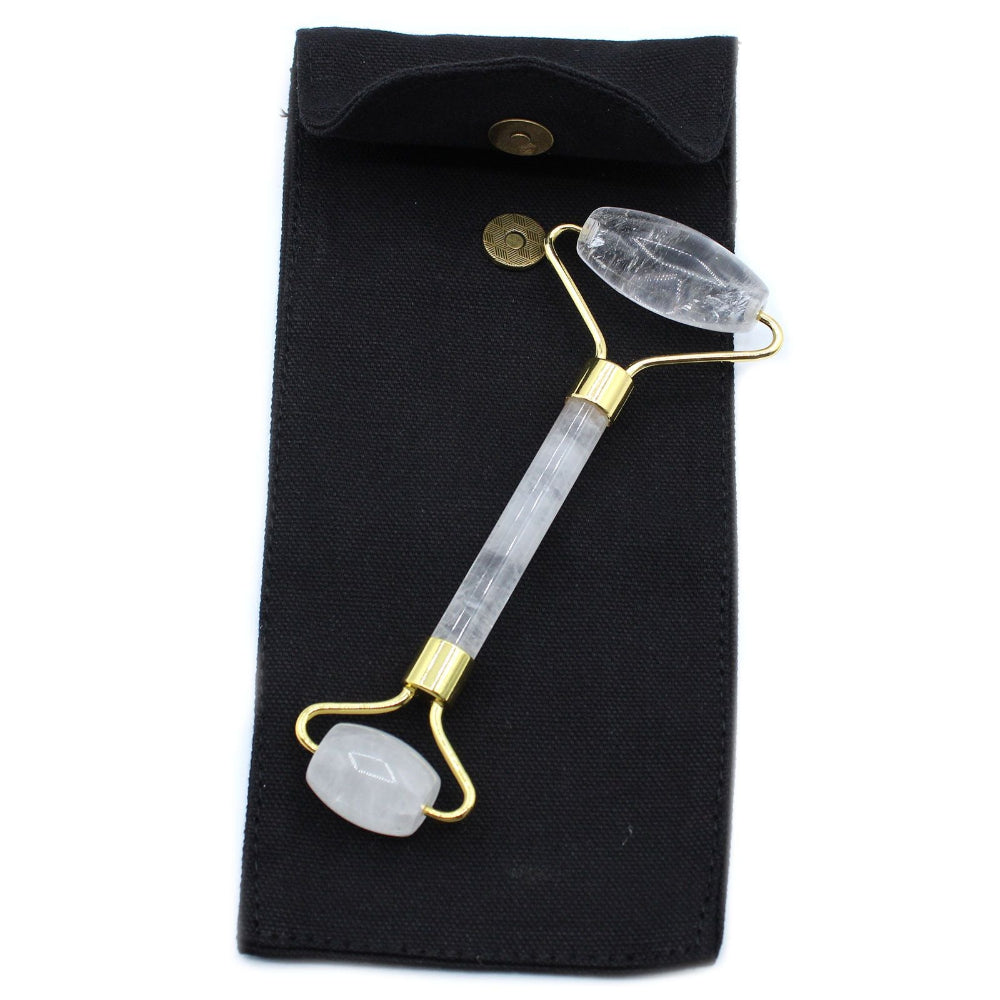 Glowing crystal face roller with gold accents on a black pouch