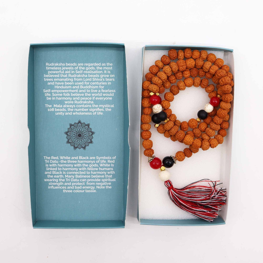 Mala beads with a tassel in a box, accompanied by a blue information card on a white background