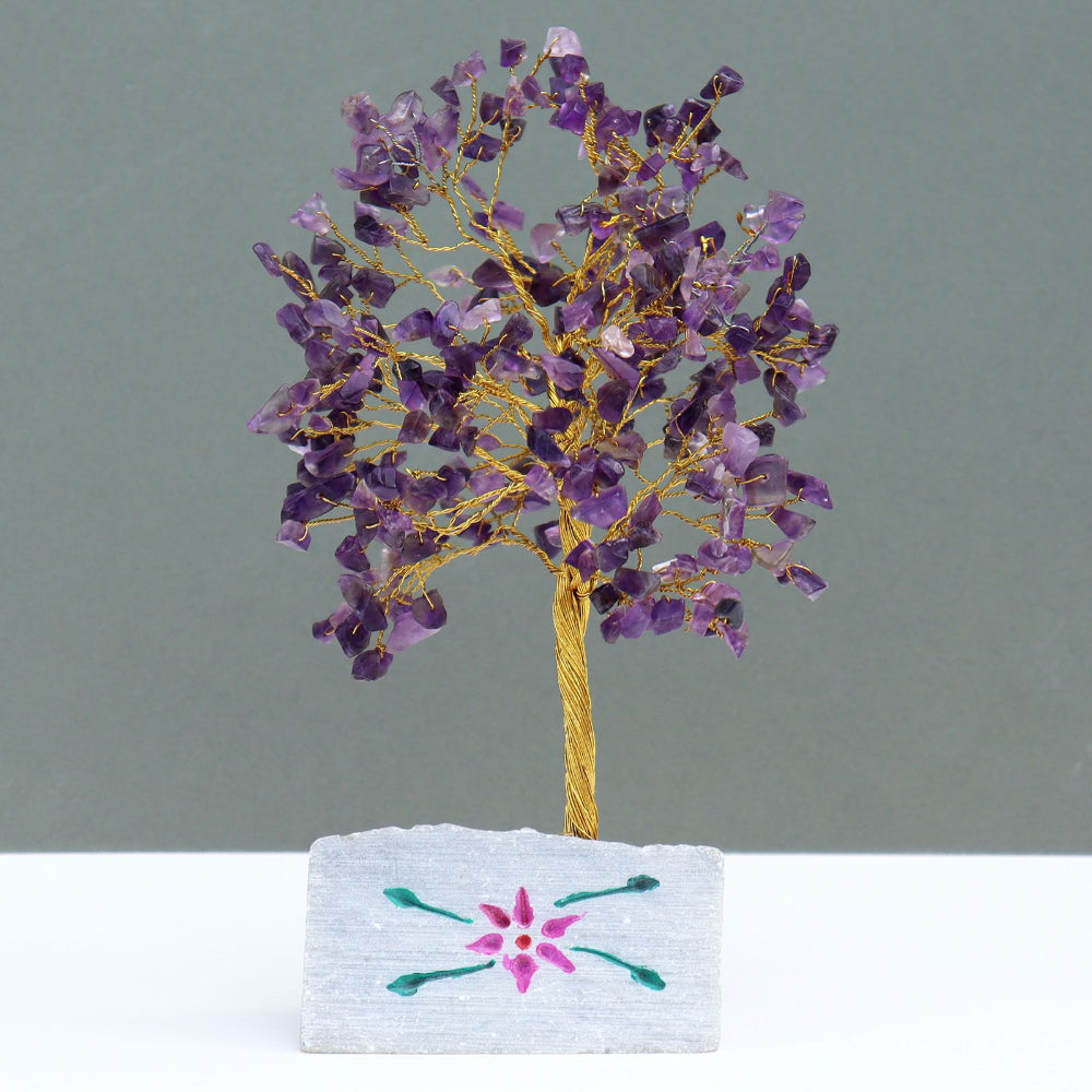 Decorative tree made of purple stones on a white base with floral design against a gray background
