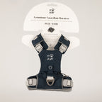 A navy blue and gray dog harness with silver buckles, displayed on its white cardboard packaging card. The brand 'PAW' is clearly visible on the harness and the packaging.