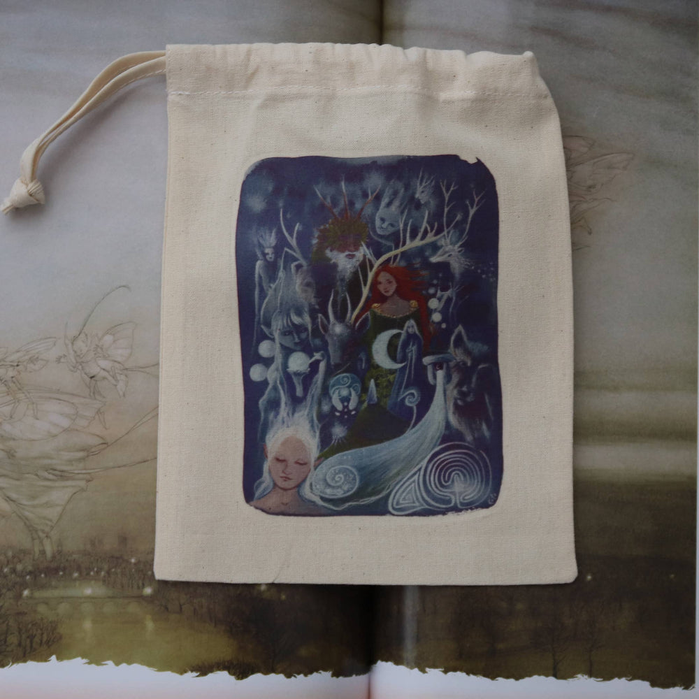 A cream-colored fabric drawstring pouch featuring a central square illustration of fantasy woodland characters in shades of blue, purple, and red, displayed on an open book.
