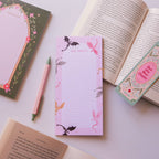 Notepad with fairy design, pen, and bookmark on an open book