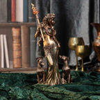Bronze statue of hecate on a pedestal with books and candles in the background
