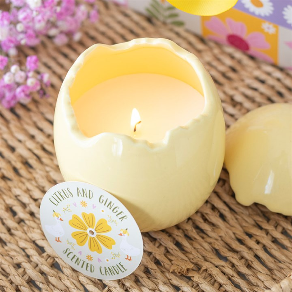 Yellow candle in an eggshell with a floral label on a woven surface